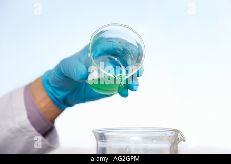 Scientist pouring green liquid into beaker, close-up of hand Stock Photo