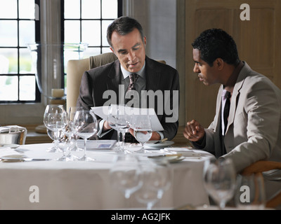 Two business men sitting at restaurant table analyzing documents Stock Photo