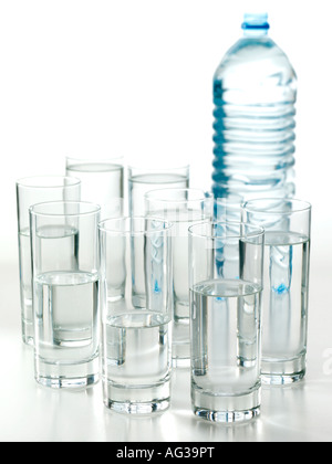 A bottle and eight glasses of water on a white background Stock Photo