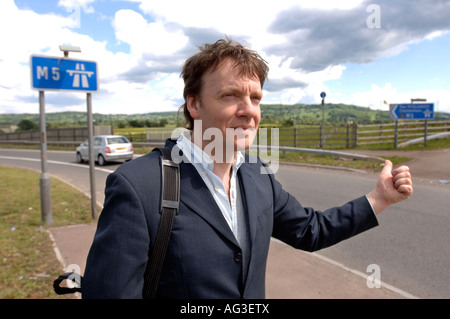 A MAN HITCH HIKING AT A MOTORWAY JUNCTION ON THE M5 UK Stock Photo