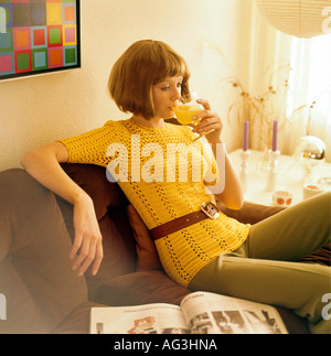 people, women, 1960s, woman sitting on a cord sofa and drinking orange juice, half length, fashion, 60s, historic, historical, pullover, crocheted, crochet, pageboy style, 20th century, female, Stock Photo