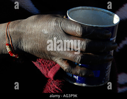 Close-up view of gnarled African hand holding old tin can as a coffee mug; Lesotho, Africa Stock Photo
