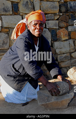 Basotho woman grinding maize/corn the traditional way in hollow rock, Lesotho, Africa Stock Photo