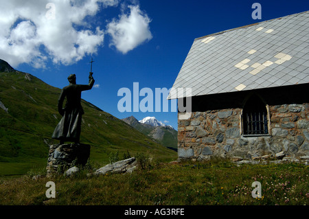 small church and statue holding cross at the petit col du st bernard in the french alps with mont blanc in the distance