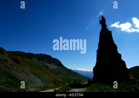 Statue of saint bernard silhouetted against the sun at the petit col du st bernard in the french alps alpine france Stock Photo