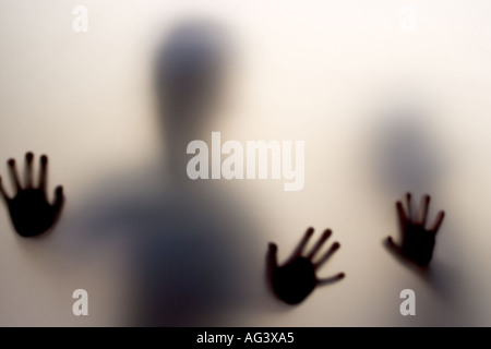 The hands of children pressed up against the frosted glass of a door Stock Photo