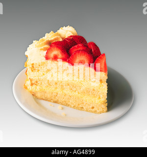 Piece of cake. Strawberry and cream victoria sponge layer cake on a white plate. Studio still life plain background. Stock Photo