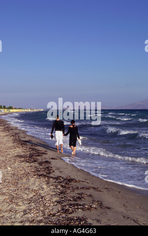 Young couple taking an early morning romantic strole along Tigaki beach on the Greek Island of Kos Stock Photo