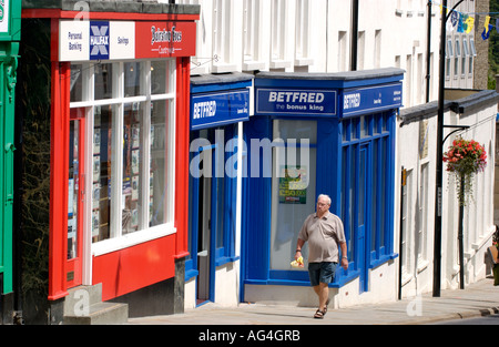 Man walking past colourful shops on main shopping street of Chepstow Monmouthshire South East Wales UK Stock Photo