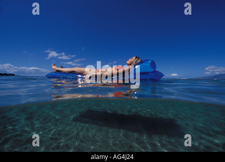 An above and below view of girl floating on a blue mat in Lahaina, Maui, Hawaii. Stock Photo