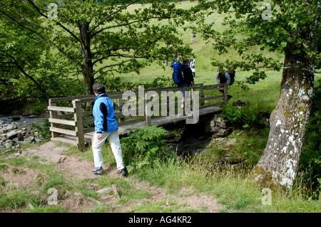 Guided walking group crossing footbridge over stream on the Taff Trail in Brecon Beacons National Park Powys South Wales UK Stock Photo