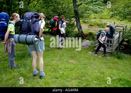 Guided walking group crossing footbridge over stream on Taff Trail in Brecon Beacons National Park Powys South Wales UK