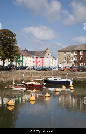 Attractive colourful quayside Georgian houses reflected in calm water of harbour with moored boats Aberaeron Ceredigion