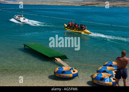 Rubber inflatable yellow rubber banana behind running speedboat on Zrce beach, Pag island in Croatia, Europe Stock Photo