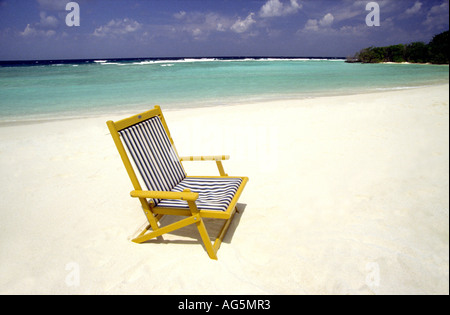 Maldives Kuredu resort striped deck chair on empty beach Stock Photo