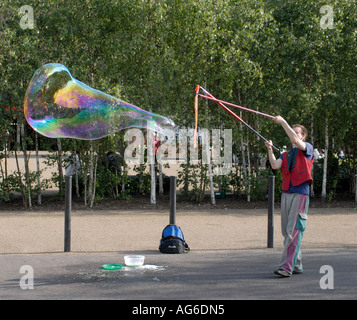 A street performer blows giant soap bubbles with rainbow colours outside the New Tate Gallery Southwark London UK 23 June 2006 Stock Photo