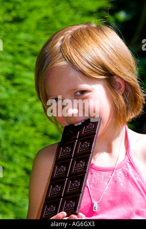 Child eating a large bar of dark chocolate. Stock Photo
