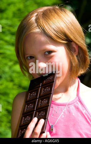 Child eating a large bar of dark chocolate. Stock Photo