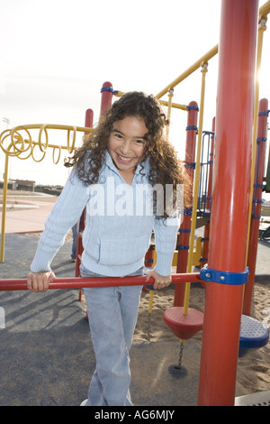 ten year old hispanic girl pulling up on gym bars outdoors Stock Photo