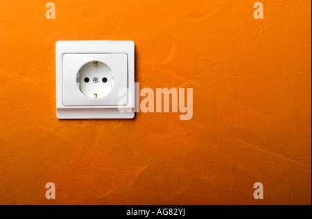 Electric wall plug at a orange wall Stock Photo