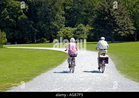 Two senior citizens ride bicycles in the park of castle Herten, Ruhr area, North Rhine-Westphalia, NRW, Germany | Stock Photo