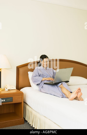 Asian Young Chinese Oriental Woman Laying On Bed In Hotel Room Working On Laptop Computer Bangkok Thailand Stock Photo