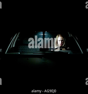 Caucasian Female Sat Alone In a Car at Night Illuminated by the Interior Light Stock Photo