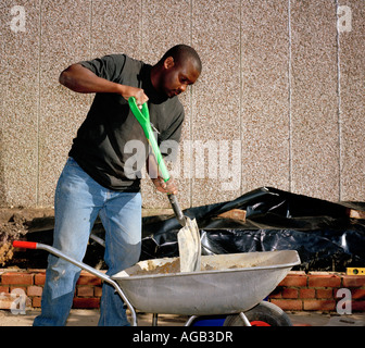 Black man mixing mortar in a wheelbarrow. Stock Photo