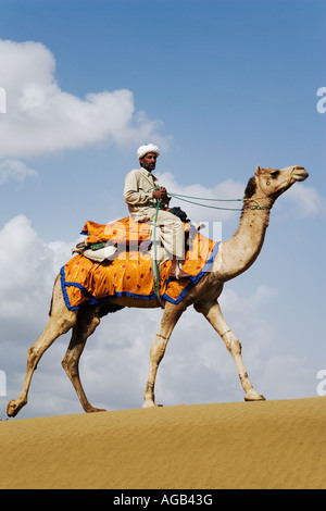 Camel with driver walking through the Great Thar desert outside Jaisalmer Rajasthan India Model Released Stock Photo