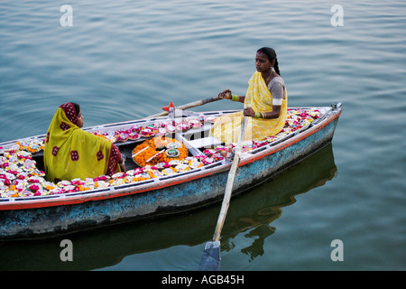 Two woman in a boat on the Ganges River selling deepak or oil lamps Ganges River  Varanasi india Stock Photo