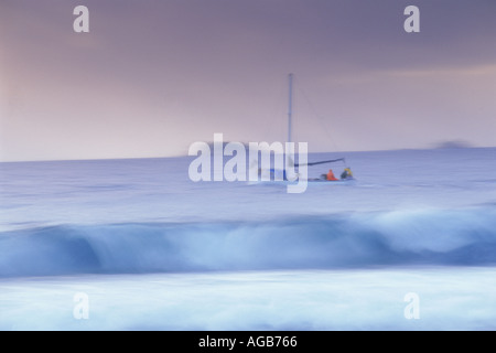 Fishing boat passing beyond shore breaking waves in Seychelles Stock Photo
