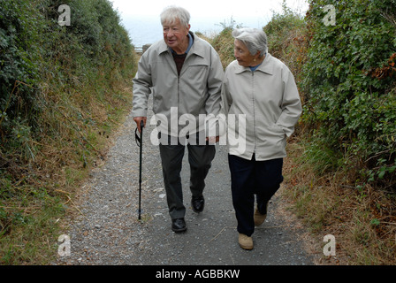Elderly couple walking along country lane and holding hands Stock Photo