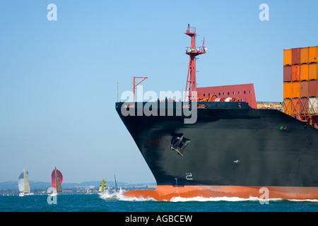 A huge container ship makes its way through a yacht filled waterway Stock Photo