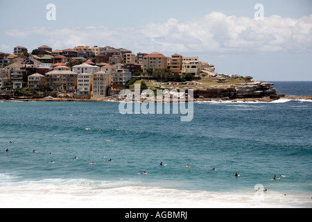 People swimming and waiting for surf waves with units or appartment buildings beyond at Bondi Beach Sydney New South Wales NSW  Stock Photo