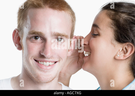 Side profile of a young woman whispering to a young man Stock Photo