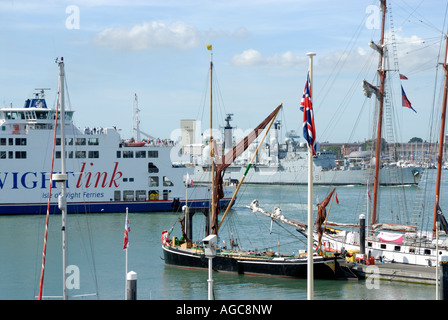 Isle of Wight ferry waits for HMS Nottingham (D91), is a batch two Type 42 Destroyer of the Royal Navy, entering Portsmouth Naval Base past Moored Yachts  on Pontoons at Gunwharf Quay, Portsmouth Stock Photo