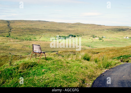 A single chair overlooking pasture land and rolling hills in the Isle of Skye Stock Photo
