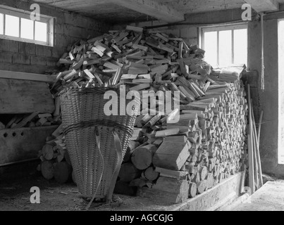 Swiss rural life, storage building containing piles of wood logs and an old traditional basket Stock Photo