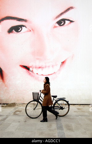 A woman walks past an advertising billboard for a new property development in Beijing China Stock Photo