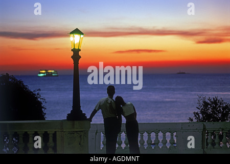 Couple on wall at sunset under lamp in Colonia del Sacramento in Uruguay Stock Photo