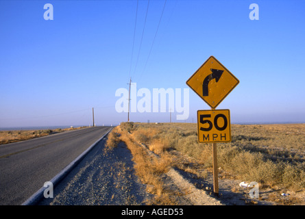 Long lonely California Desert highway stretches into the distance, a 50MPH right turn sign in the foreground Stock Photo