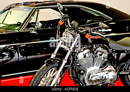 Front side view photo of a custom built chopper motorcycle with a 1960 s black Chevy Impala as a background Stock Photo