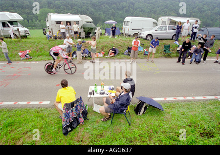Spectators watch the Tour de France time trial 2004 at the side of the road while having a picnic with wine Stock Photo