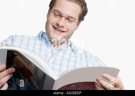 Close-up of a young man reading a magazine and smiling Stock Photo