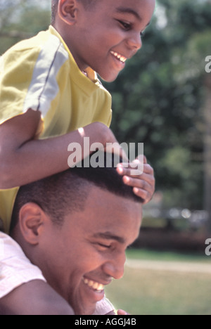 African American father carrying son on shoulders Stock Photo