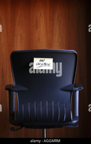 on vacation written on a post it note sticked on a armchair in an office environment Stock Photo