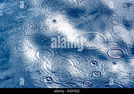 raindrops hitting water surface and creating ripples Stock Photo