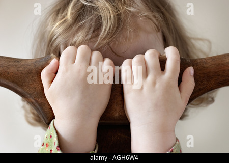 young child hiding behind hands Stock Photo