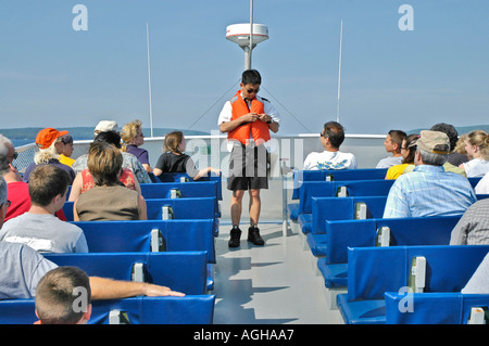 Asian American male demonstrates the proper use of a life vest on a boat tour on Lake Superior Michigan Upper Peninsula Stock Photo