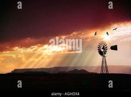 A windmill blowing on the open range in the southwest at sunset Stock Photo